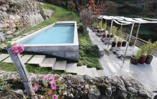 uma piscina num jardim com vasos de plantas em Casas Da Lapa, Nature & Spa Hotel em Seia