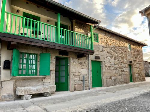 un edificio de piedra con puertas verdes y balcón en A Parada House by Kev, en Parada del Sil