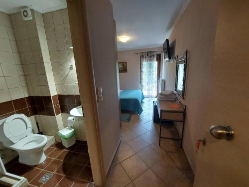 un bagno con servizi igienici e una camera con un letto di Ziakas Rooms a Zákas