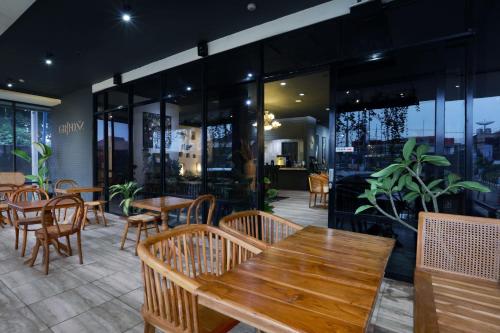 a restaurant with wooden tables and chairs and windows at Algoritma Hotel in Palembang