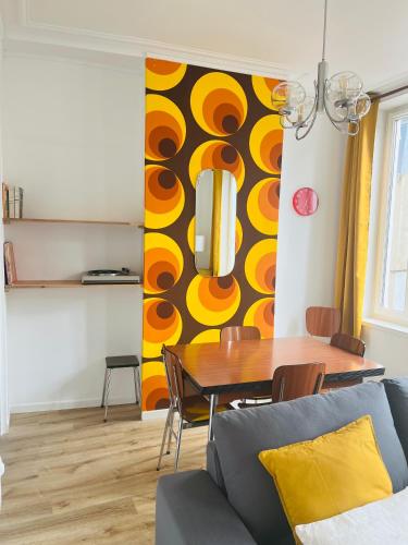 une salle à manger avec une table et un mur jaune dans l'établissement Le Vintage 70's, 4 à 6 pers, centre-ville, à Boulogne-sur-Mer