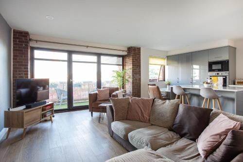 a living room with a couch and a tv and a kitchen at New Lisburn Road Apartment - Free Parking in Belfast