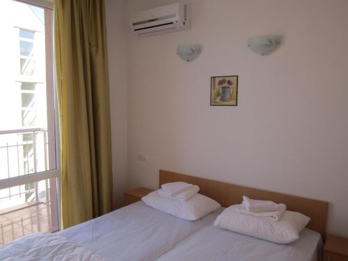a bedroom with a bed with white sheets and a window at Guest Rooms Venera in Primorsko