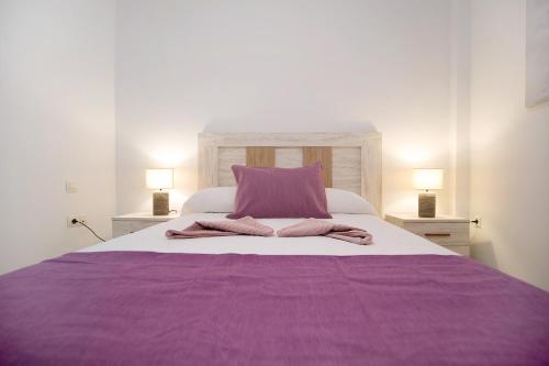 a large bed with a purple blanket and two lamps at Casita Amiga del Mar in Gran Tarajal