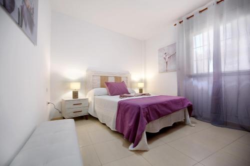 a white bedroom with a bed and a window at Casita Amiga del Mar in Gran Tarajal
