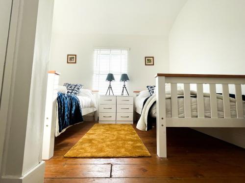 a bedroom with two twin beds and a crib at Central Cheltenham House - By Suitely in Cheltenham
