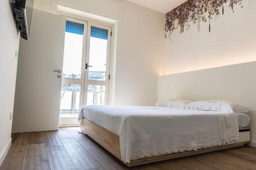 a white bedroom with a bed and a large window at DOMUS PINAE Casa vacanze in Pescara