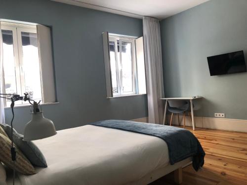 a bedroom with a bed and two windows at Godinho's House in Matosinhos