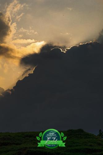 a cloudy sky with a green logo in front of a field at Finca Hotel Betel in San Carlos