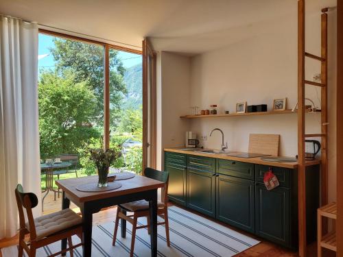 una cucina con armadi verdi, tavolo e finestra di Apartma Hiša 6 a Bohinj