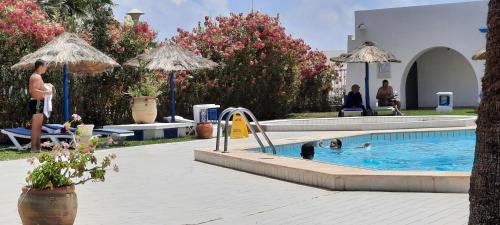 a swimming pool with people in the water and umbrellas at Le Bleu Céleste in Hammamet