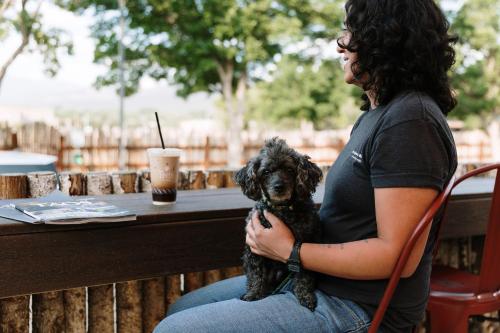 a woman sitting on a bench holding a dog at Taos Valley Lodge in Taos