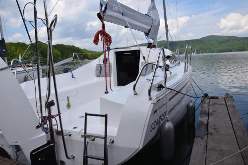 Biała łódź zakotwiczona w doku w wodzie w obiekcie Phobos 24,5 Yacht w Polańczyku