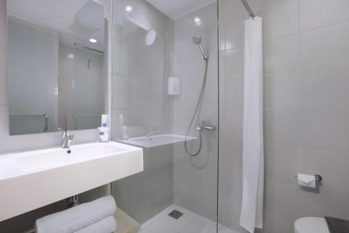 y baño blanco con lavabo y ducha. en Algoritma Hotel, en Palembang