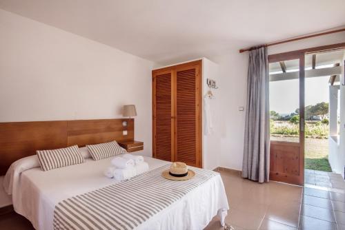 una camera da letto con un letto con un cappello sopra di Bungalows Es Pins - Emar Hotels a Playa Migjorn