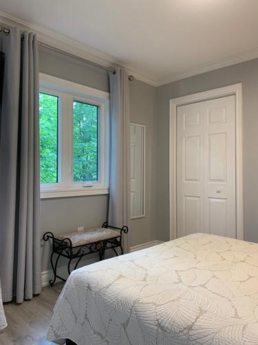 a bedroom with a bed and a window and a bench at Ambiance by the Falls Cozy Suite in Niagara Falls