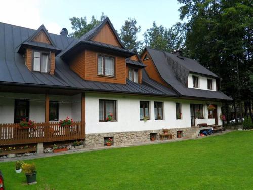a house with a gambrel roof with a green yard at Pokoje gościnne Kozica in Zakopane