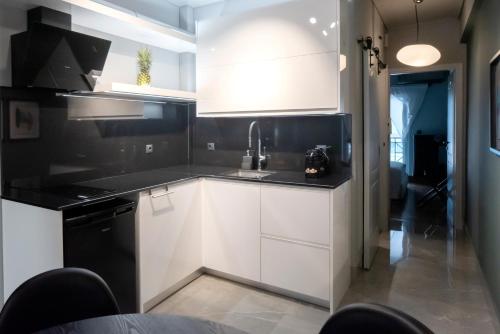 a kitchen with white cabinets and black counter tops at Luxury Premium Suite #5 in Chalkida