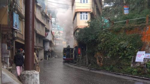 a train on a street in a city at DukeRaj Homestay in Darjeeling