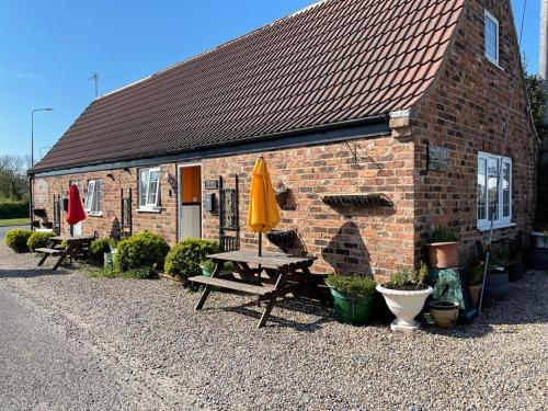 a brick building with a picnic table and a yellow umbrella at Yarm cottages sleeping 12 Next to Fox Covert Pub in Kirk Leavington