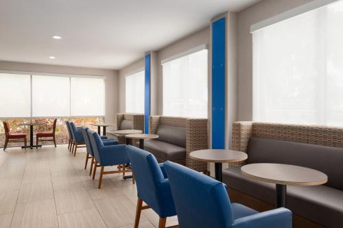 a waiting room with tables and blue chairs at Holiday Inn Express Vero Beach-West I-95 by IHG in Vero Beach