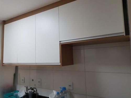 una cocina con armarios blancos sobre un fregadero en Jockey Family Chamonix 3, en Vila Velha