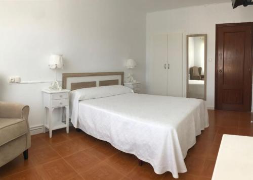 a white bedroom with a bed and a chair and a couch at Hostal Casa Enrique in Barres