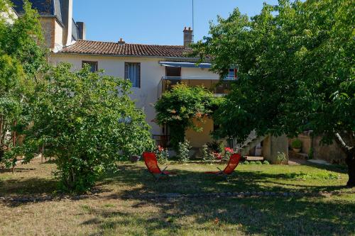 duas cadeiras vermelhas no quintal de uma casa em Les Chambres de la Vallée em Argenton-Château