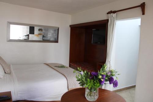 a bedroom with a bed and a vase of flowers on a table at El Serafin Hotel Boutique in Querétaro