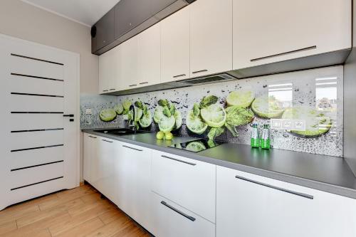 a kitchen with white cabinets and green vegetables on the counter at APARTAMENTY PIAMOLA Willa Zacisze Kąty Rybackie in Kąty Rybackie