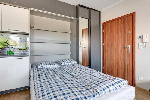 a bedroom with a bed with a blue and white checkered blanket at APARTAMENTY PIAMOLA Willa Zacisze Kąty Rybackie in Kąty Rybackie