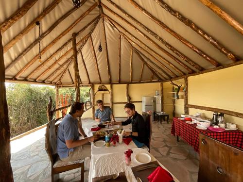 馬賽馬拉的住宿－Olaloi Mara Camp，三人坐在帐篷里的桌子上