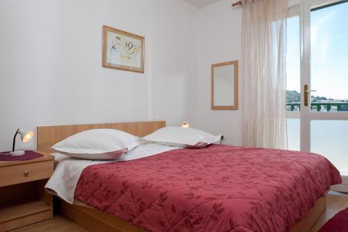 a bedroom with a bed with a red blanket and a window at Apartments Waterfront IVAN 2 in Podgora