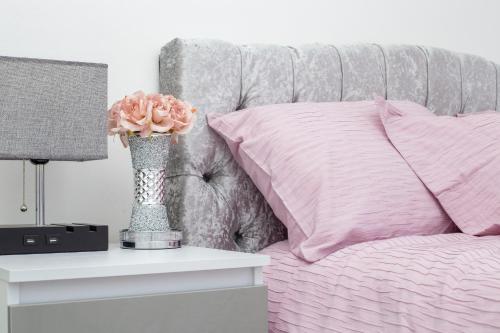 a vase with a pink flower on a bed at Dream Home Near Stratford Olympic Park London in London