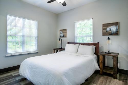 1 Schlafzimmer mit einem weißen Bett und 2 Fenstern in der Unterkunft Pine Cove Cabin - Hot Tub, Game Room, Theater Room in Pigeon Forge