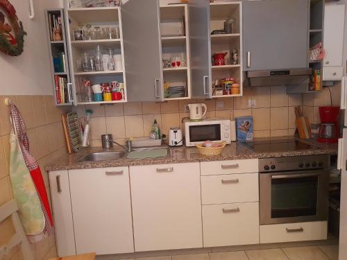 a kitchen with white cabinets and a sink and a microwave at Family Apartman in Jagodina