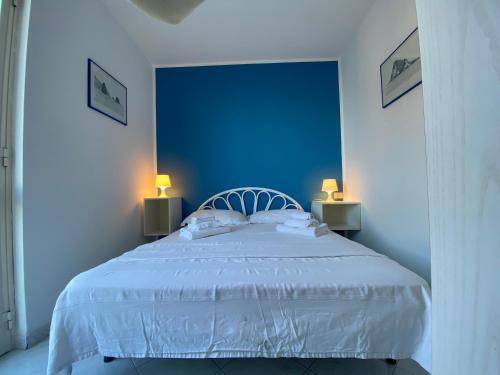 a blue bedroom with a white bed with two lamps at CannetoMare in Canneto