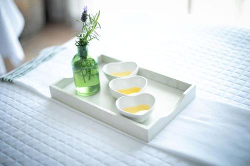 a tray with three cups and a bottle on a bed at 1 Hotel San Francisco in San Francisco