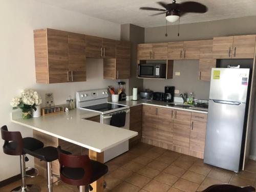 eine Küche mit Holzschränken und einem weißen Kühlschrank in der Unterkunft Apartamento Chorotega in Liberia
