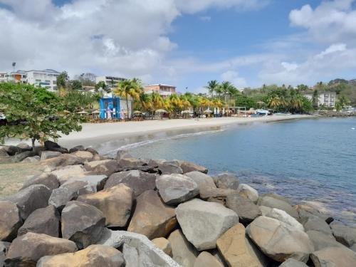 a beach with rocks and the ocean and buildings at Bougainvilliers in Schœlcher
