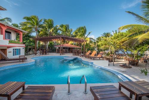 a pool at a resort with tables and chairs at Bella Vista Resort Belize in San Pedro