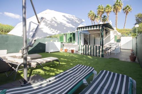 a yard with two chairs and a house with a mountain at Charming bungalow with private garden in Maspalomas
