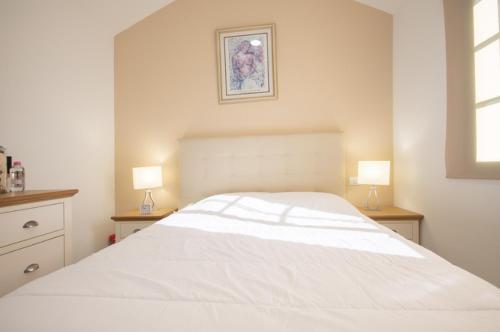 a white bed in a bedroom with two lamps at Charming bungalow with private garden in Maspalomas