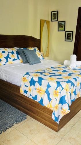 a bed with a blue and yellow floral comforter at Garden Hut in Victoria