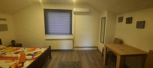 1 dormitorio con cama, escritorio y ventana en Little house, Mandrina 13, en Sarajevo