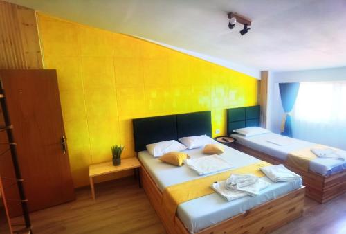 - une chambre avec 2 lits et un mur jaune dans l'établissement Casa Laura, à Mangalia