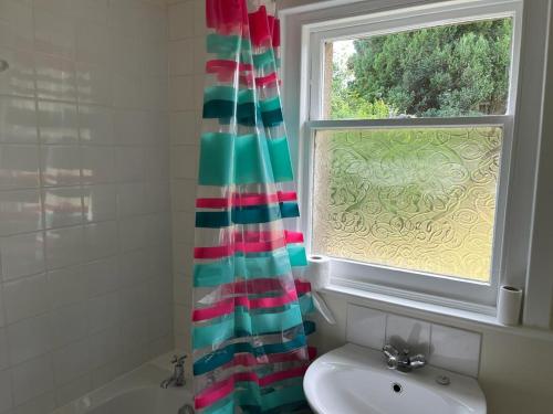 a bathroom with a window and a shower curtain at Willow Cottage in Kinloss