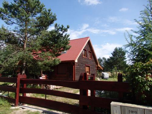a red house with a fence and trees at Trójmiasto nad jeziorem DOM -ECHOCHATA in Kamień