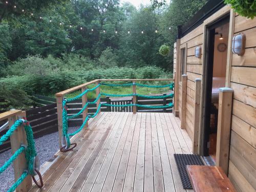 a wooden deck with a wooden door and stairs at The Cabin, Stronua. A beautiful 1 bedroom cabin. in Fort Augustus