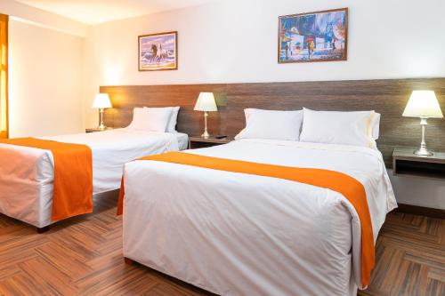 a hotel room with two beds with orange and white sheets at Hotel Plaza San Antonio Arequipa in Arequipa